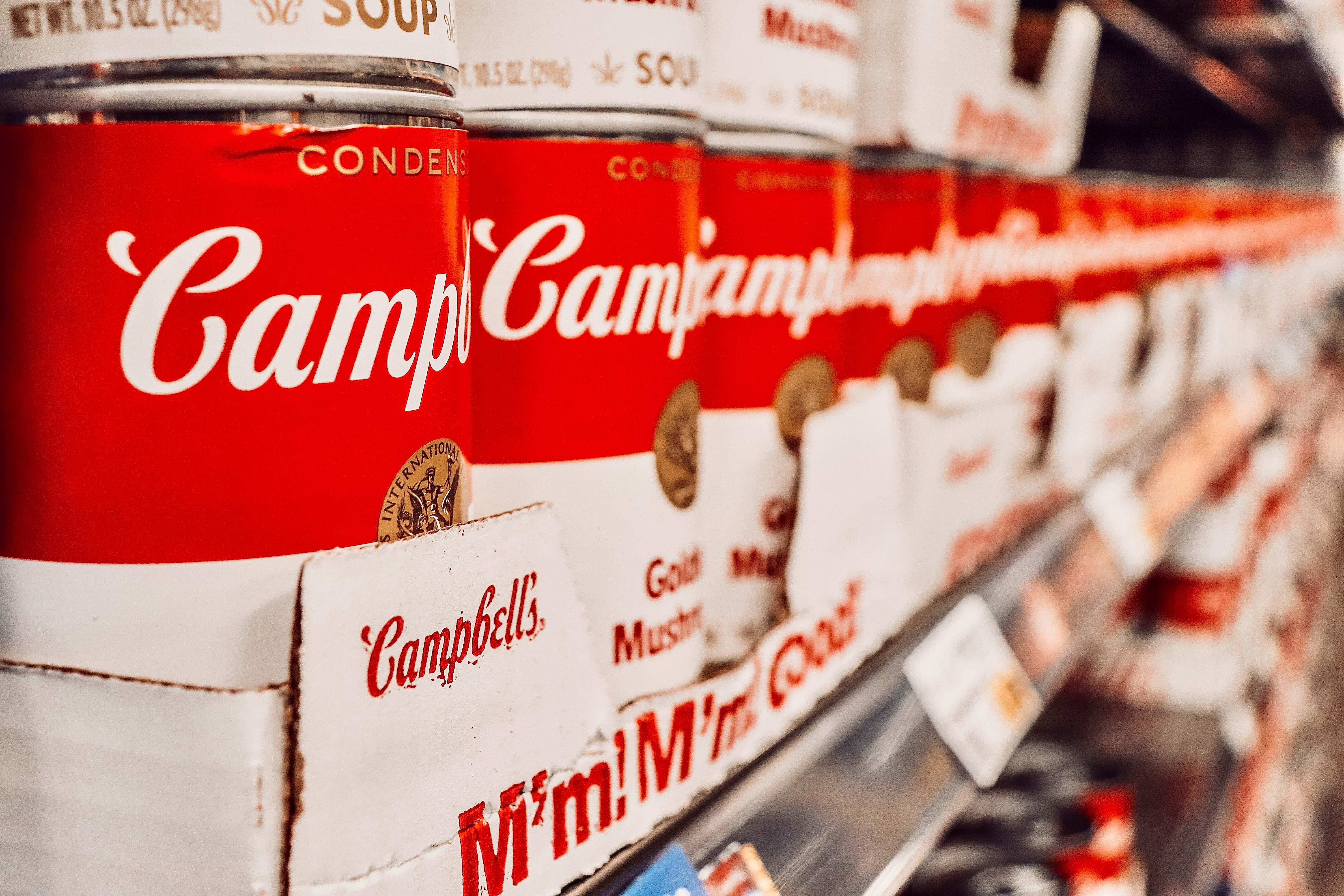 A shelf of identical tins of Campbell’s Soup | Photo by Kelly Common on Unsplash